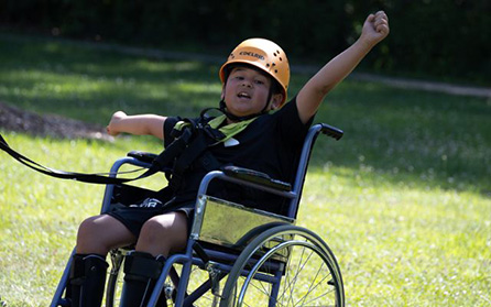 George throws his arms up in the air after conquering the high ropes course at Easter Seals camp. 